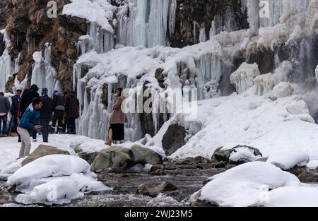 Baramulla, Inde. 12 février 2024. Les touristes prennent des photos Infront de cascade partiellement gelée pendant une journée ensoleillée. Après un long hiver sec et chaud, la vallée a connu des chutes de neige et des pluies généralisées la semaine dernière. La vallée est actuellement dans la phase modérée de l'hiver, Chillai Khurd, après la fin de la période la plus dure de 40 jours le 30 janvier. Crédit : SOPA images Limited/Alamy Live News Banque D'Images