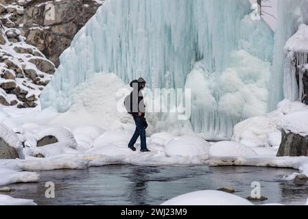 Baramulla, Inde. 12 février 2024. Un homme marche sur des glaçons gelés formés par une fuite de pipe à eau pendant une journée ensoleillée. Après un long hiver sec et chaud, la vallée a connu des chutes de neige et des pluies généralisées la semaine dernière. La vallée est actuellement dans la phase modérée de l'hiver, Chillai Khurd, après la fin de la période la plus dure de 40 jours le 30 janvier. Crédit : SOPA images Limited/Alamy Live News Banque D'Images