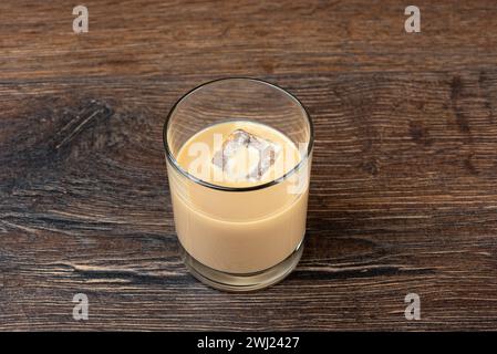 Glaçon dans un verre avec de la liqueur de crème irlandaise originale sur une table en bois. Copier l'espace. Banque D'Images