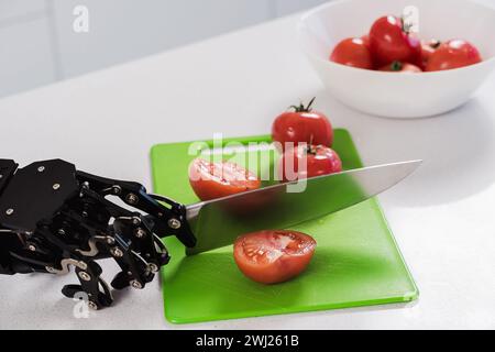 La main du vrai robot coupant des tomates fraîches avec un couteau tranchant. Concept d'automatisation de processus robotisée Banque D'Images