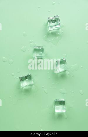 Concept de froid et rafraîchissant. Glaçons avec des gouttes d'eau sur un fond vert. Banque D'Images