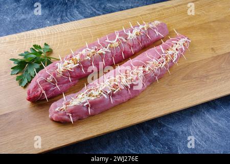 Filet de porc cru Mangalica farci de noix hachées et de citrouille offert en gros plan sur une planche à découper design en bois Banque D'Images