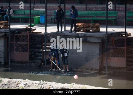 Collecte des restes de bois au temple de Pashupatinath sur la rive du crématorium sacré de la rivière Bagmati, Katmandou, Népal, le lundi 12 février 2024 Banque D'Images