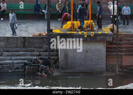 Collecte des restes de bois au temple de Pashupatinath sur la rive du crématorium sacré de la rivière Bagmati, Katmandou, Népal, le lundi 12 février 2024 Banque D'Images