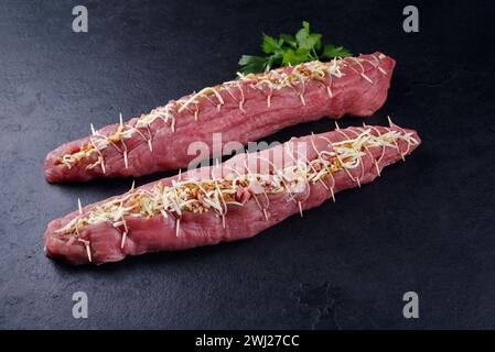 Filet de porc cru Mangalica farci de noix hachées et de citrouille offert en gros plan sur un tableau noir avec copie spa Banque D'Images