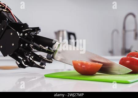 La main du vrai robot coupant des tomates fraîches avec un couteau tranchant. Concept d'automatisation de processus robotisée Banque D'Images