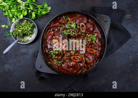 Ossobuco alla milanese braisé traditionnel italien avec gremolata au vin blanc et sauce au veau servi dans un ragoût en fonte Banque D'Images