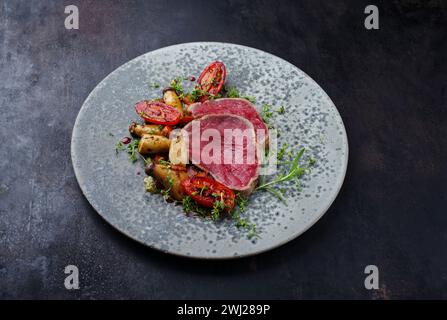 Steak de filet de bœuf chianina italien frit très rare avec champignons et tomates servis en gros plan dans un bol au design nordique avec c Banque D'Images