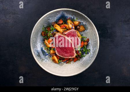 Steak de filet de bœuf chianina italien frit très rare avec champignons et carottes servis comme vue de dessus dans un bol design nordique avec co Banque D'Images