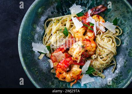 Crevettes royales frites traditionnelles avec des pâtes italiennes tagliatelli et du parmesan servies comme vue de dessus sur un bol design avec texte s. Banque D'Images