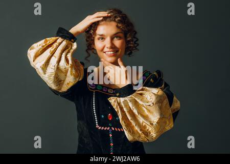 Portrait d'une jeune femme aristocratique vêtue d'une robe médiévale touchant la peau du visage sur fond sombre. Banque D'Images