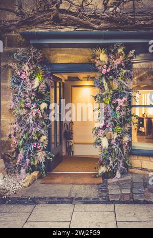 Guirlande florale autour d'une porte de magasin dans le village typiquement anglais de Broadway dans les Cotswolds Banque D'Images