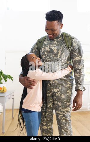 Heureux soldat afro-américain embrassant sa fille à la maison, espace de copie Banque D'Images