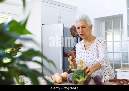 Couple senior diversifié déballage de l'épicerie dans la cuisine Banque D'Images