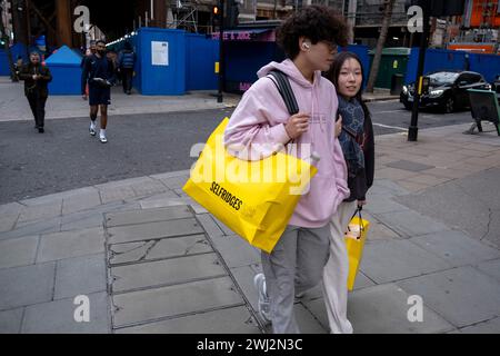 Acheteurs et visiteurs sur Oxford Street transportant des sacs Selfridges le 4 février 2024 à Londres, Royaume-Uni. L’Office for National Statistics ONS a révélé que décembre a vu la chute la plus marquée des ventes au détail depuis la pandémie de coronavirus et que les gens ont fait leurs achats en novembre, profitant des ventes plus tôt. Oxford Street est un grand centre commercial dans le West End de la capitale et est la rue commerçante la plus fréquentée d'Europe avec environ un demi-million de visiteurs quotidiens dans ses quelque 300 magasins, dont la majorité sont des magasins de mode et de vêtements de grande rue. Banque D'Images