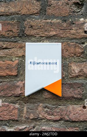 Un panneau blanc avec un surlignement orange sur un mur de briques indiquant en néerlandais que ce bâtiment est monument national (Rijksmonument), Banque D'Images