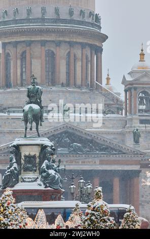 Russie, Saint-Pétersbourg, 30 décembre 2023 : les gens marchent parmi les arbres de Noël dans de fortes chutes de neige, un parc organisé en vacances près de se réunir La cathédrale d'Isaac Banque D'Images