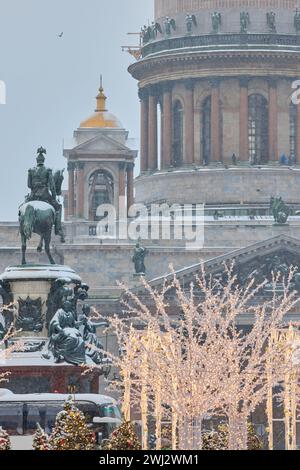 Russie, Saint-Pétersbourg, 30 décembre 2023 : les gens marchent parmi les arbres de Noël dans de fortes chutes de neige, un parc organisé en vacances près de se réunir La cathédrale d'Isaac Banque D'Images