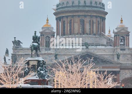 Russie, Saint-Pétersbourg, 30 décembre 2023 : les gens marchent parmi les arbres de Noël dans de fortes chutes de neige, un parc organisé en vacances près de se réunir La cathédrale d'Isaac Banque D'Images