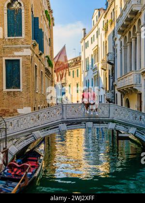 Couple d'hommes et de femmes lors d'un voyage en ville à Venise Italie assis à un pont au-dessus des canaux de Venise Banque D'Images