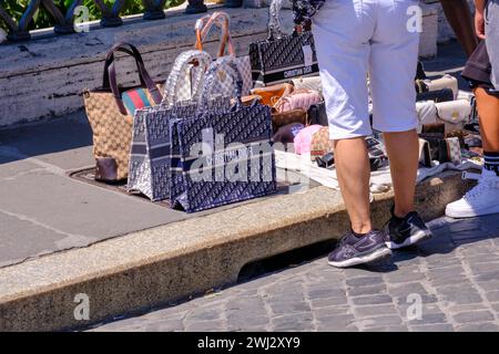 Rome, IT - 11 août 2023 : les gens regardent des sacs de couterfeit vendus par un vendeur ambulant Banque D'Images