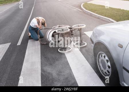 Mère horrifiée sur le passage pour piétons après un accident de voiture quand un véhicule heurte son bébé landau. Banque D'Images