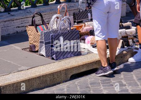 Rome, IT - 11 août 2023 : les gens regardent des sacs de couterfeit vendus par un vendeur ambulant Banque D'Images