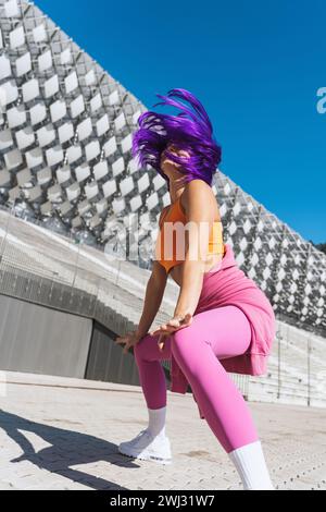 Danseuse femme active insouciante portant des vêtements de sport colorés s'amusant dans la rue Banque D'Images