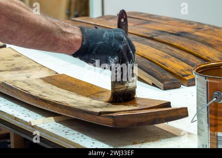 Lasurer. Peinture de boiseries. Bâtons Bourbon Barrel sur table de travail dans un atelier. Main de Handyman varn Banque D'Images