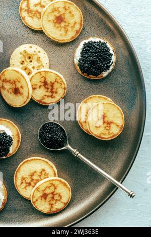 Blinis au caviar noir et au fromage à la crème, abattu par le haut sur un plat festif Banque D'Images
