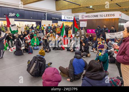 Leeds, Royaume-Uni. 12 FÉVRIER 2024. Des manifestants pro-palestiniens rassemblés se rassemblent et organisent un sit-in sur le sol de la gare de Leeds pour protester contre les actions israéliennes à Rafah. Montre BTP à distance. Crédit Milo Chandler/Alamy Live News Banque D'Images