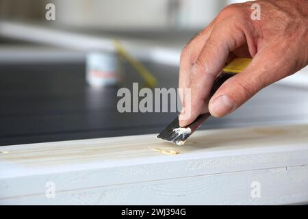 Boiseries. Couteau à mastic dans la main de l'homme. Travailleur de bricolage appliquant du mastic sur le bois. Suppression des trous Banque D'Images