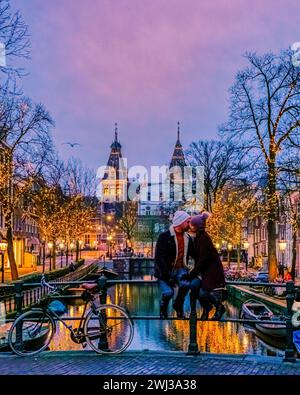 Couple sur les canaux néerlandais d'Amsterdam avec des lumières de noël en décembre Banque D'Images