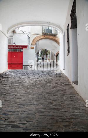 Un réfrigérateur rouge vif orne une ruelle étroite sous une arche dans la ville de Cadaques en Catalogne Banque D'Images