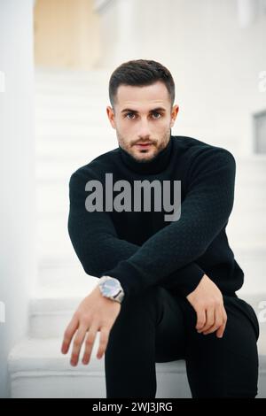Portrait de beau jeune homme dans une tenue de vêtements noirs sur fond blanc moderne Banque D'Images
