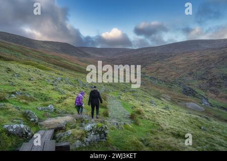 Mère et fille marchant sur un sentier à Glendalough avec vue sur une vallée et un ruisseau. Randonnée dans les belles montagnes de Wicklow d'automne, Irlande Banque D'Images