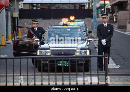 Chauffeurs de taxi et taxis à un stand à l'extérieur de la gare d'Ishiyama près de Kyoto au Japon. Banque D'Images