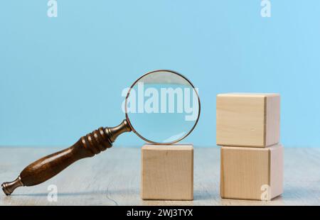 Cubes en bois et loupe sur fond bleu Banque D'Images