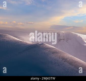 La neige couvrait les montagnes d'hiver en plein soleil le soir dernier. Magnifique crépuscule venteux sur les sommets au-dessus de la pittoresque station de ski alpin Banque D'Images