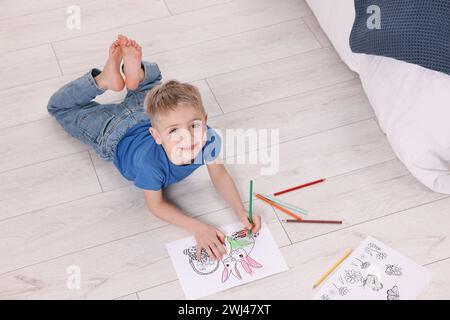 Mignon petit garçon coloriant sur le sol chaud à la maison. Système de chauffage Banque D'Images