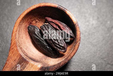 Haricots Tonka dans une cuillère en bois sur un fond sombre Banque D'Images