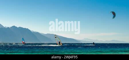 Les véliplanchistes et les kitesurfeurs roulent dans la mer Rouge sur le fond de la côte rocheuse en Egypte Dahab Sud Sinaï Banque D'Images