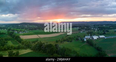 Une belle vue aérienne panoramique sur les nuages et le coucher de soleil sur les belles terres agricoles verdoyantes du comté de Lancaster, en Pennsylvanie. Banque D'Images