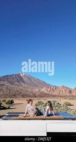 Un drone capture un homme et une femme assis sur un van garé dans la pittoresque montagne du volcan Teide à Tenerife. Banque D'Images