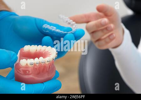 Orthodontiste montrant le modèle de la mâchoire humaine avec des étrésillons et des aligneurs de fil expliquant la différence Banque D'Images