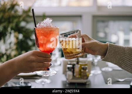 Amis toast avec des verres de whisky et cocktail de fraises Banque D'Images