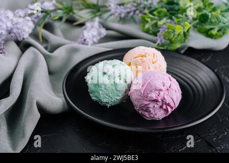 Trois boules de crème glacée sur une assiette foncée Banque D'Images