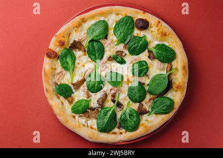 Pizza aux champignons chauds avec basilic sur assiette rouge Banque D'Images