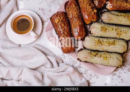 ECLAIRES françaises traditionnelles avec crème au chocolat et à la vanille et tasse d'espresso Banque D'Images