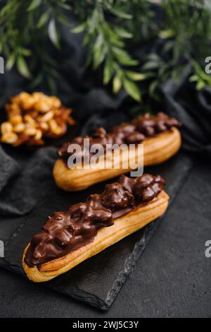 Deux eclairs avec du chocolat noir sur tableau noir Banque D'Images